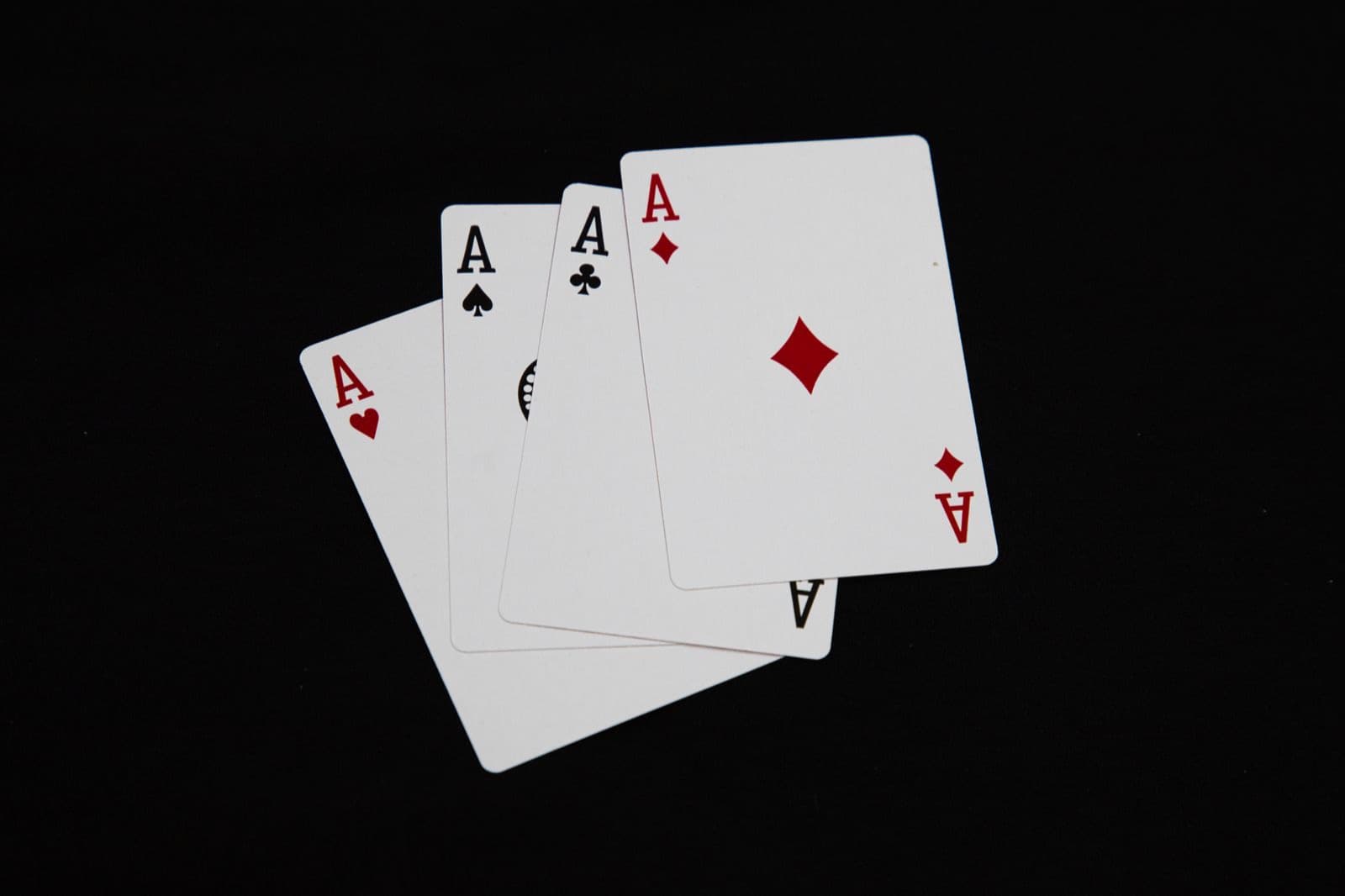 Four aces from a deck of playing cards fanned out on a black background