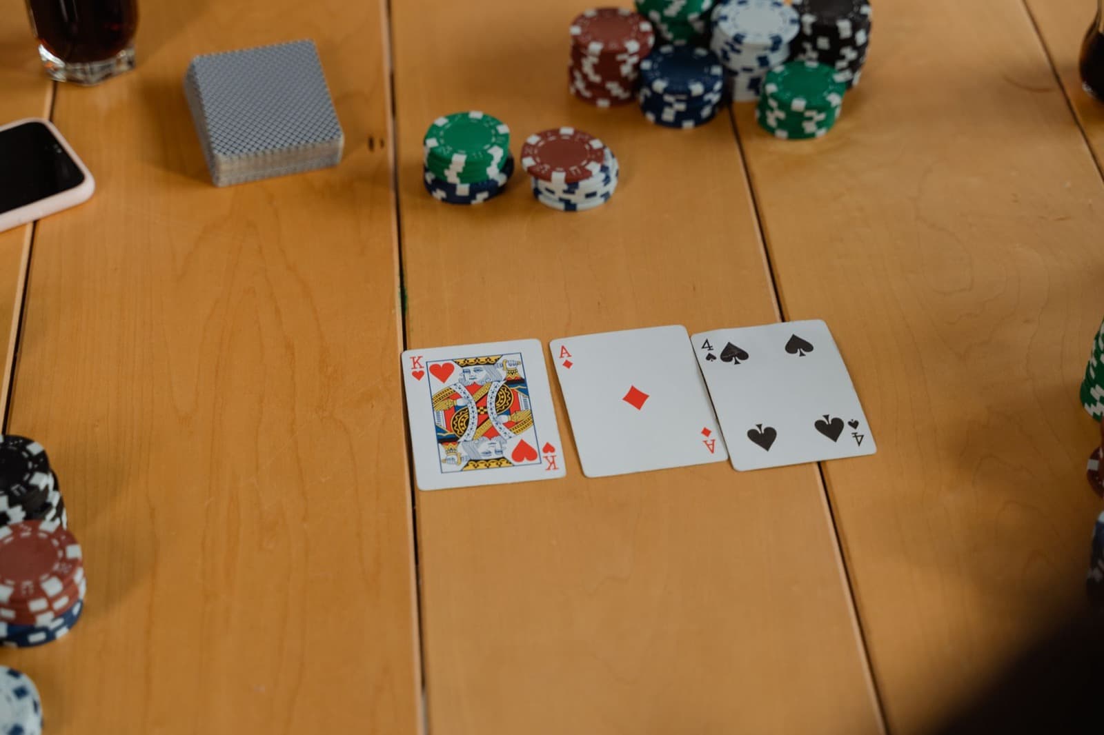 A King of Hearts, an Ace, and poker chips on a wooden table